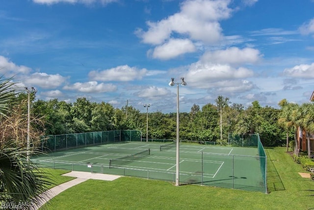 view of tennis court featuring fence and a lawn