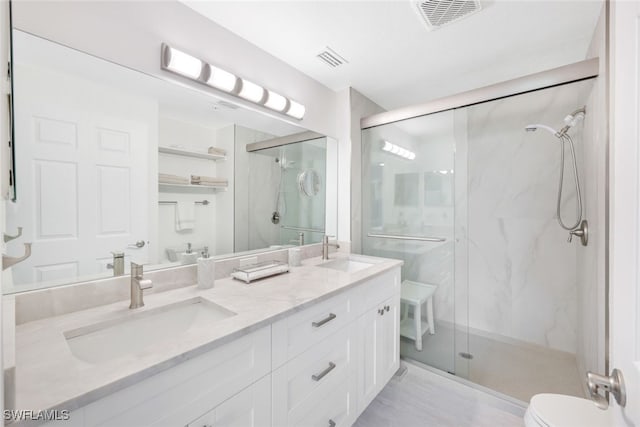 bathroom featuring toilet, a marble finish shower, a sink, and visible vents