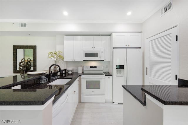 kitchen featuring a peninsula, white appliances, visible vents, and a sink