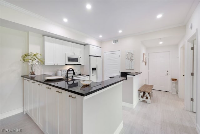 kitchen with white appliances, visible vents, a peninsula, crown molding, and white cabinetry