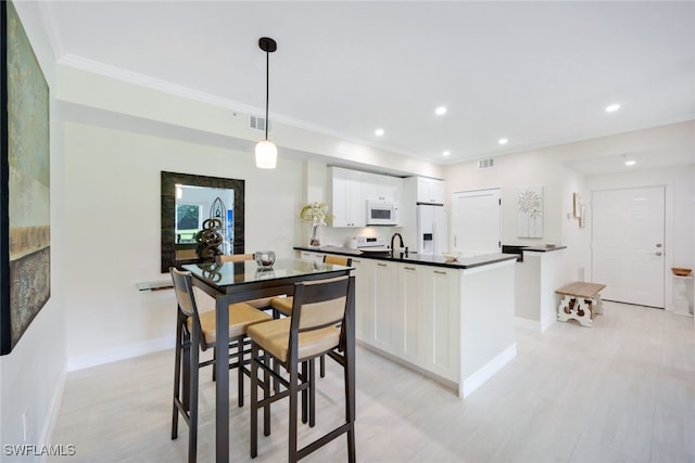 kitchen with decorative light fixtures, dark countertops, white cabinetry, white appliances, and baseboards