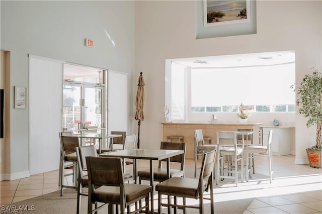 dining area featuring light tile patterned floors and a high ceiling