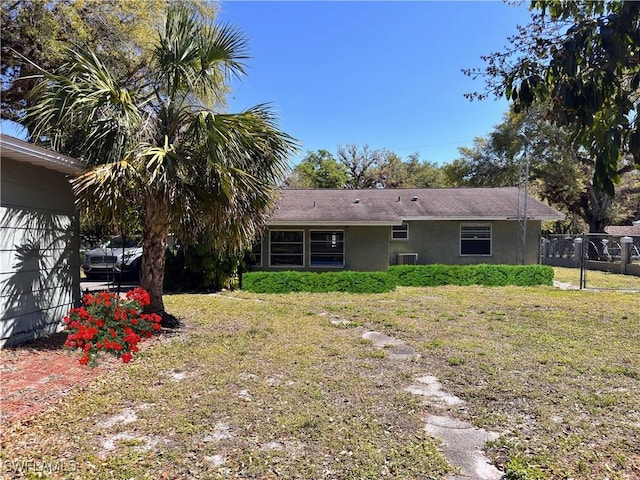 back of house with a yard, cooling unit, fence, and stucco siding