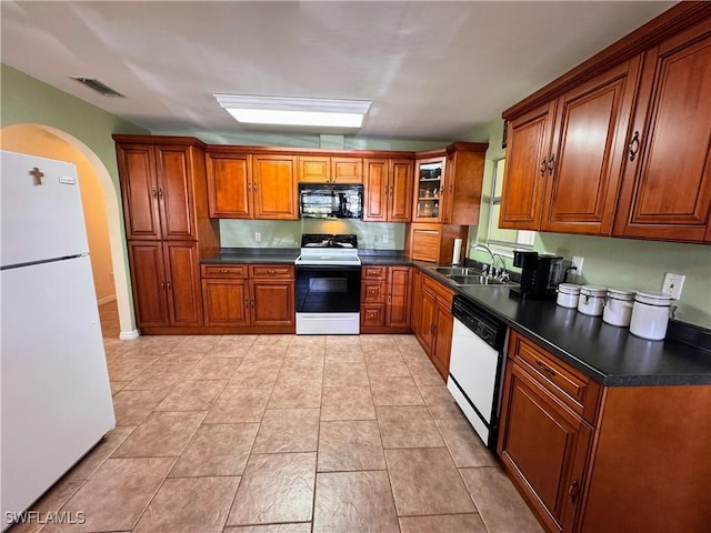 kitchen featuring brown cabinets, dark countertops, visible vents, a sink, and white appliances