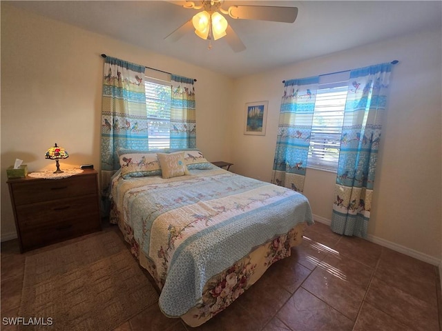 tiled bedroom with a ceiling fan, multiple windows, and baseboards