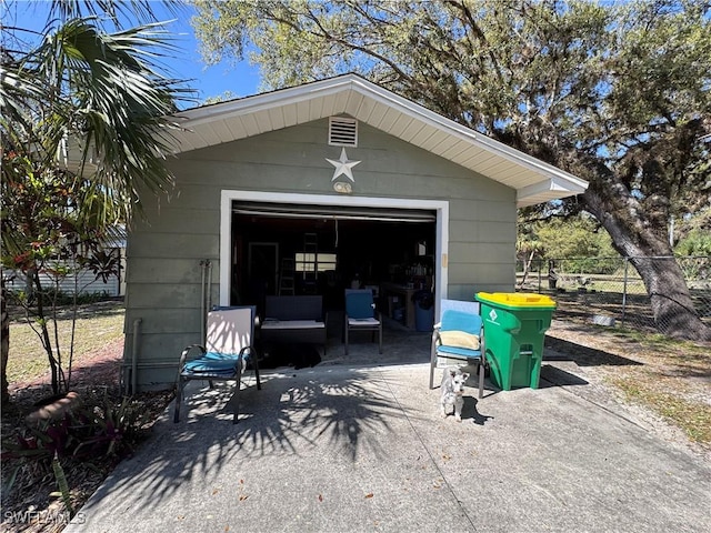 detached garage featuring driveway and fence