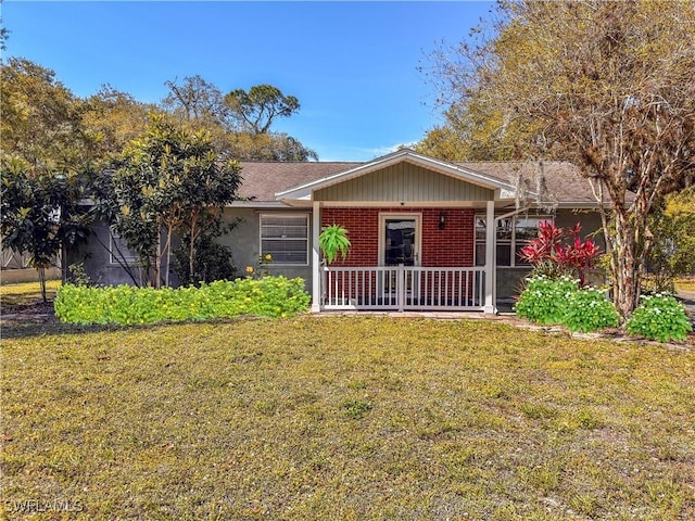 ranch-style home featuring covered porch, brick siding, and a front yard