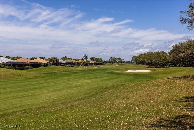 view of home's community featuring view of golf course and a yard