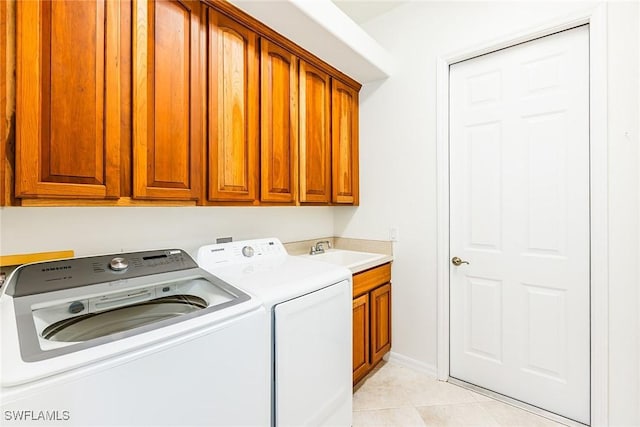 clothes washing area featuring light tile patterned floors, a sink, baseboards, independent washer and dryer, and cabinet space