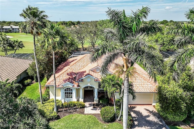 view of front of property featuring decorative driveway, a tile roof, a front lawn, and stucco siding