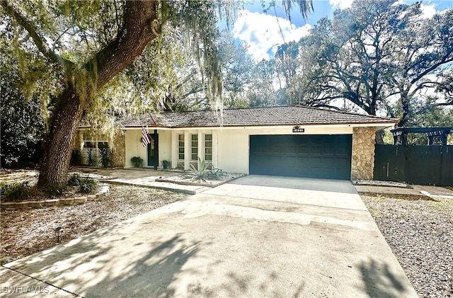 ranch-style home with concrete driveway, an attached garage, fence, and stucco siding