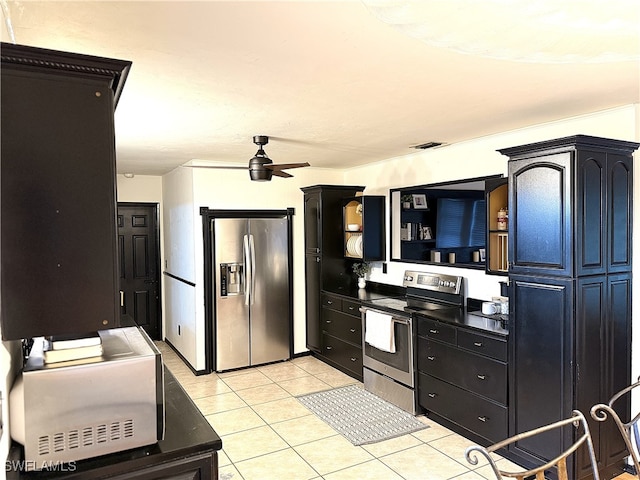 kitchen with light tile patterned floors, visible vents, a ceiling fan, dark countertops, and appliances with stainless steel finishes