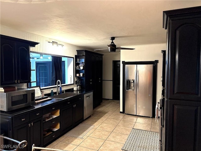 kitchen with light tile patterned floors, stainless steel appliances, dark countertops, a sink, and dark cabinetry