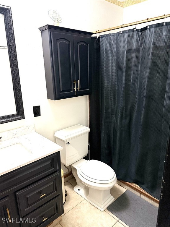 bathroom with curtained shower, vanity, toilet, and tile patterned floors