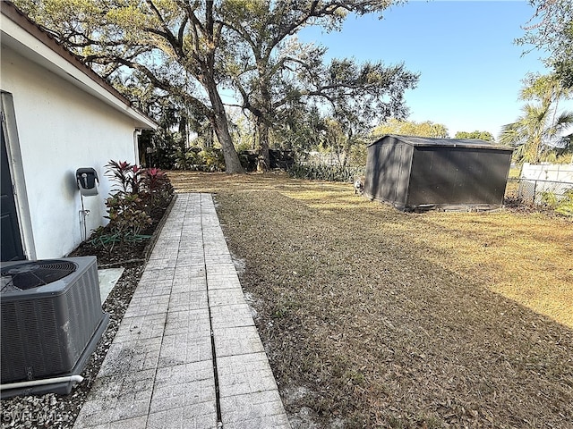 view of yard featuring an outbuilding, a storage unit, a fenced backyard, and central air condition unit