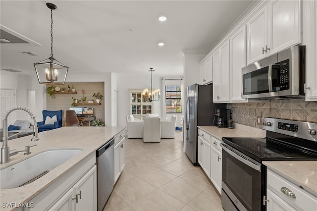 kitchen with a sink, white cabinetry, appliances with stainless steel finishes, backsplash, and an inviting chandelier