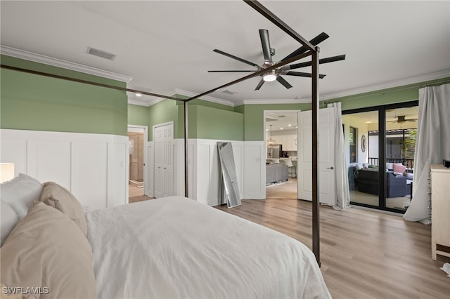 bedroom featuring a wainscoted wall, visible vents, ornamental molding, wood finished floors, and access to outside