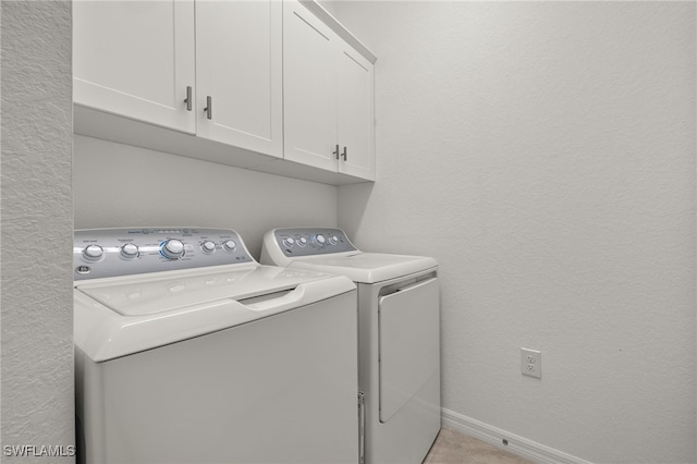 laundry room featuring cabinet space, baseboards, separate washer and dryer, and a textured wall