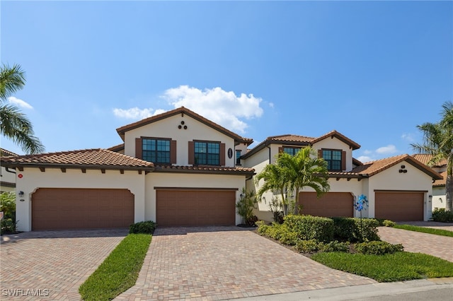 mediterranean / spanish-style home with a tiled roof, decorative driveway, and stucco siding