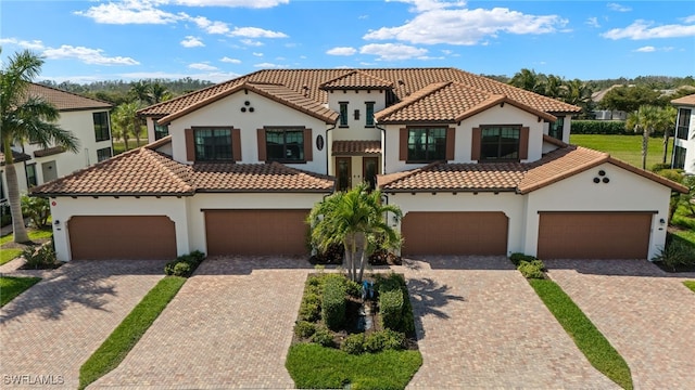 mediterranean / spanish-style house with a tiled roof, decorative driveway, and stucco siding