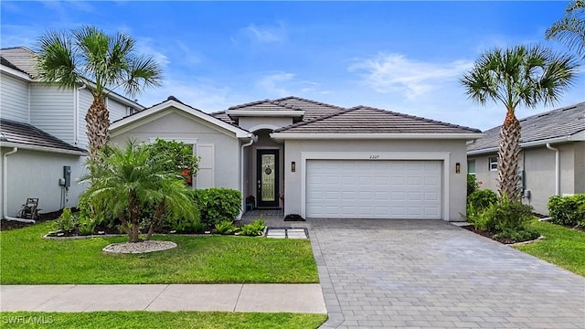 single story home with stucco siding, decorative driveway, a front yard, and a garage