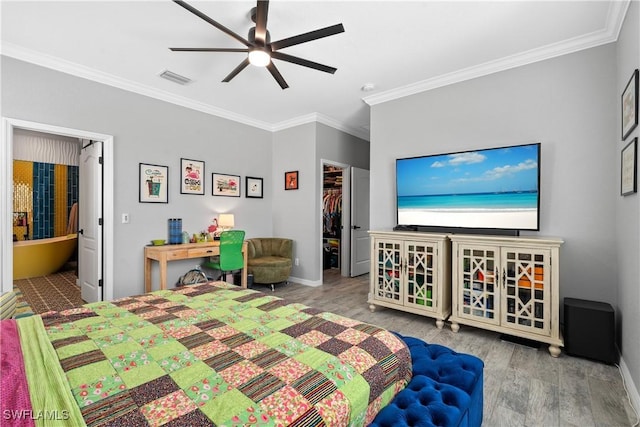bedroom featuring a spacious closet, ornamental molding, wood finished floors, and visible vents