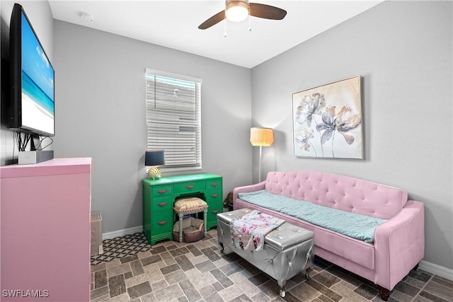 living area featuring baseboards and a ceiling fan