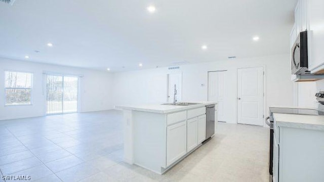 kitchen featuring a center island with sink, stainless steel appliances, light countertops, white cabinetry, and a sink