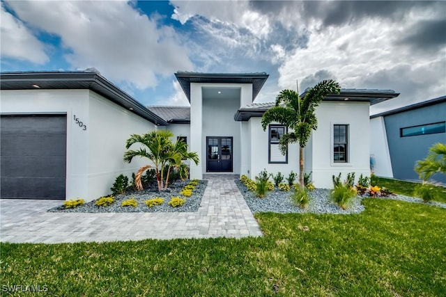 view of exterior entry featuring a garage, a lawn, and stucco siding