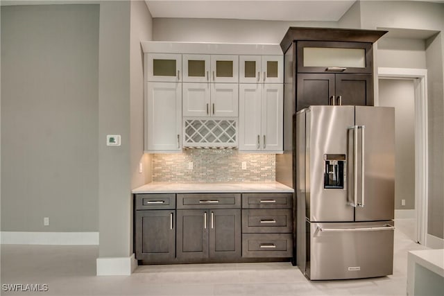 kitchen featuring tasteful backsplash, high end fridge, light countertops, and white cabinetry