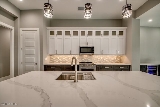 kitchen with backsplash, stainless steel appliances, a sink, and decorative light fixtures