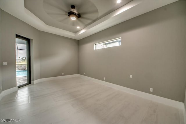 unfurnished room with a tray ceiling, baseboards, and recessed lighting