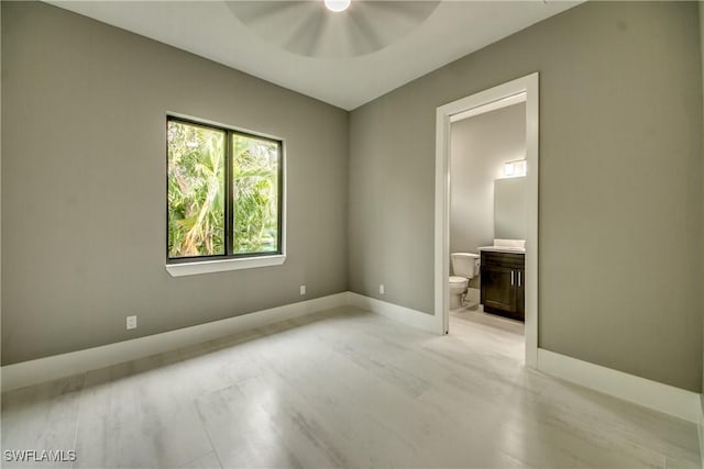 unfurnished bedroom with a ceiling fan, baseboards, and ensuite bathroom