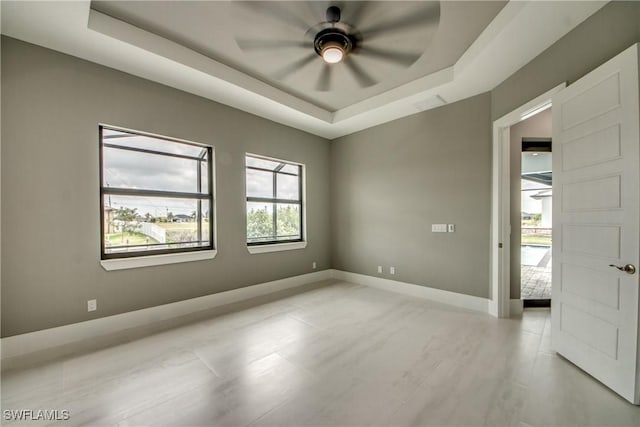 unfurnished room with visible vents, baseboards, a raised ceiling, and a ceiling fan