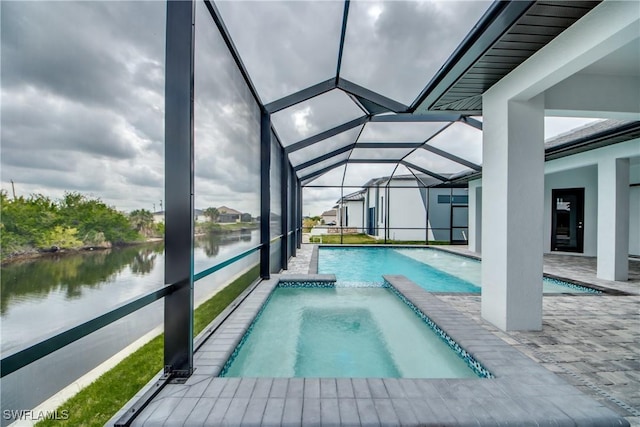 view of swimming pool with glass enclosure, a pool with connected hot tub, a water view, and a patio area