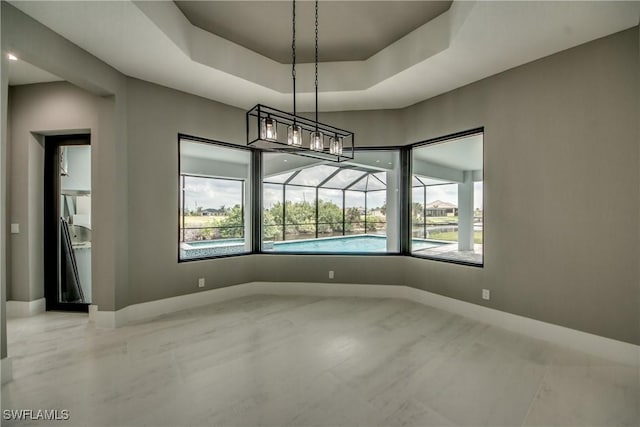 unfurnished dining area featuring a sunroom, baseboards, and a raised ceiling