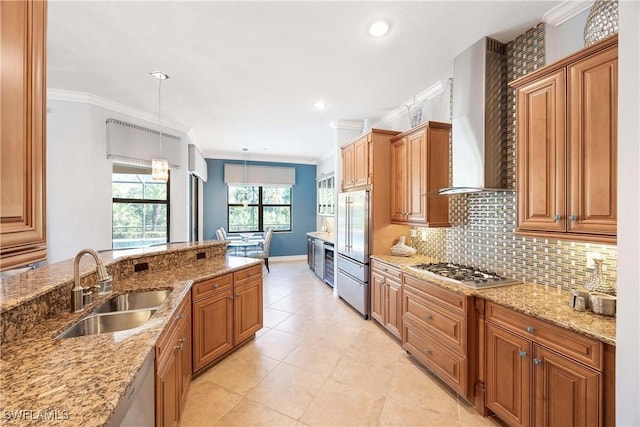 kitchen with ornamental molding, wall chimney range hood, a sink, and appliances with stainless steel finishes