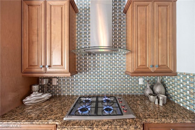 kitchen featuring wall chimney exhaust hood, brown cabinets, backsplash, and stainless steel gas stovetop