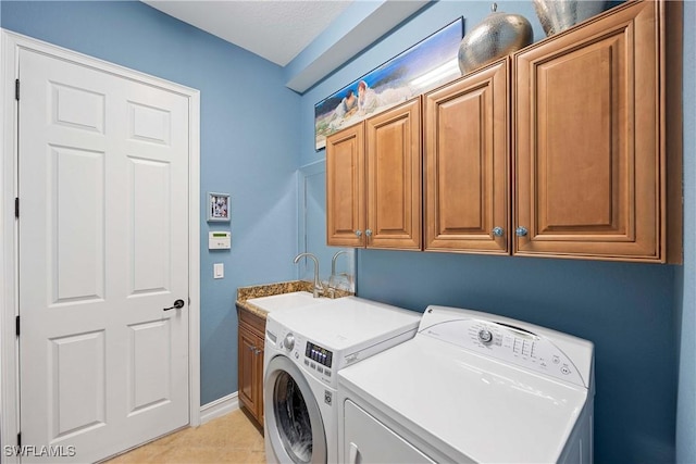 laundry area featuring light tile patterned flooring, separate washer and dryer, a sink, baseboards, and cabinet space