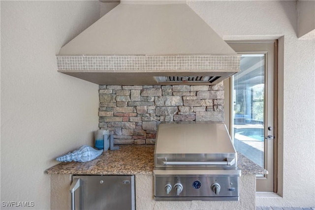 kitchen featuring stone counters, custom range hood, and fridge