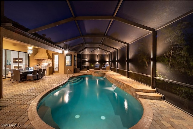 view of swimming pool featuring a patio area, glass enclosure, an outdoor kitchen, and outdoor dining space