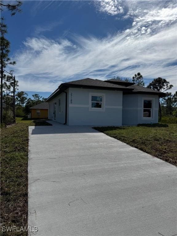 view of front of home featuring concrete driveway, a front yard, and stucco siding