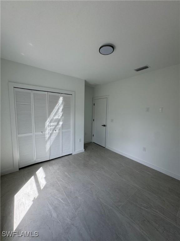 unfurnished bedroom featuring a closet, visible vents, and baseboards