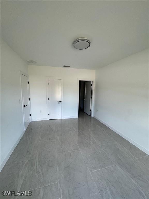 unfurnished bedroom with marble finish floor, visible vents, and baseboards