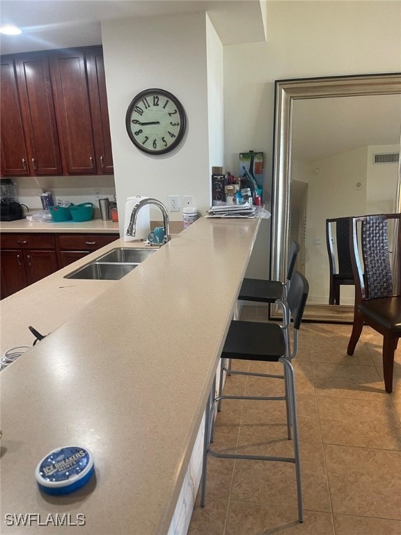 kitchen featuring light countertops, visible vents, a sink, tile patterned flooring, and a peninsula