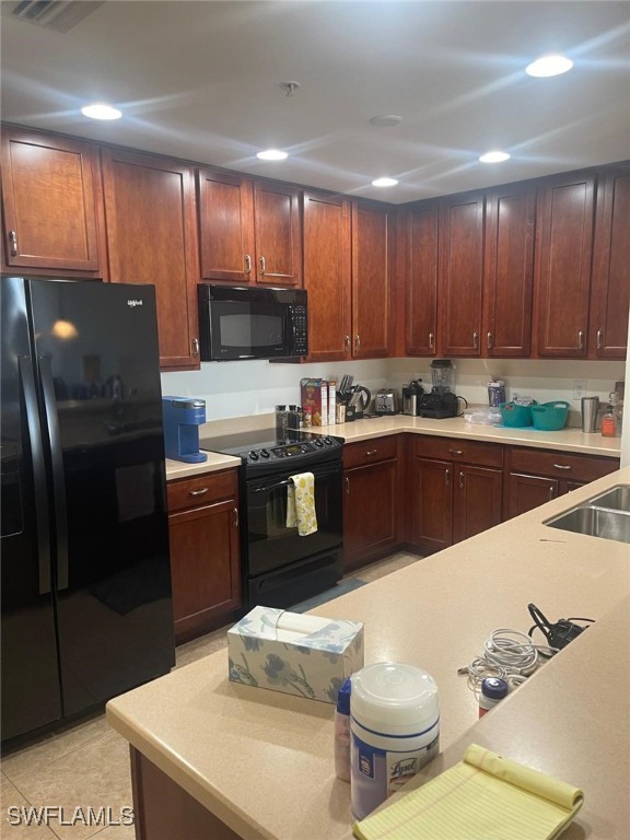 kitchen featuring a sink, black appliances, light countertops, and recessed lighting