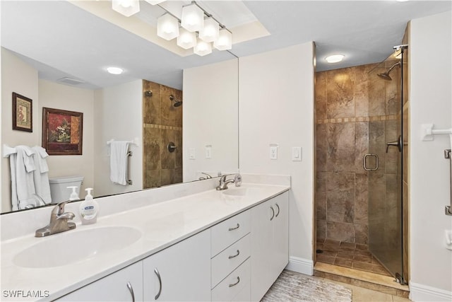 bathroom with double vanity, a stall shower, a sink, and toilet