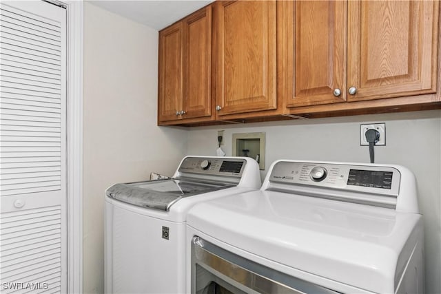 laundry room with washing machine and clothes dryer and cabinet space