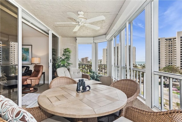 sunroom / solarium featuring a view of city and a ceiling fan