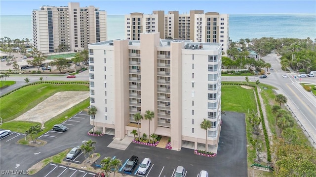 view of property with a view of city, uncovered parking, and a water view